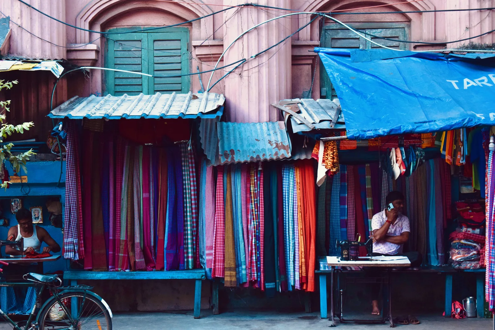 Colourful cloth stall, tailors at their sewing machines