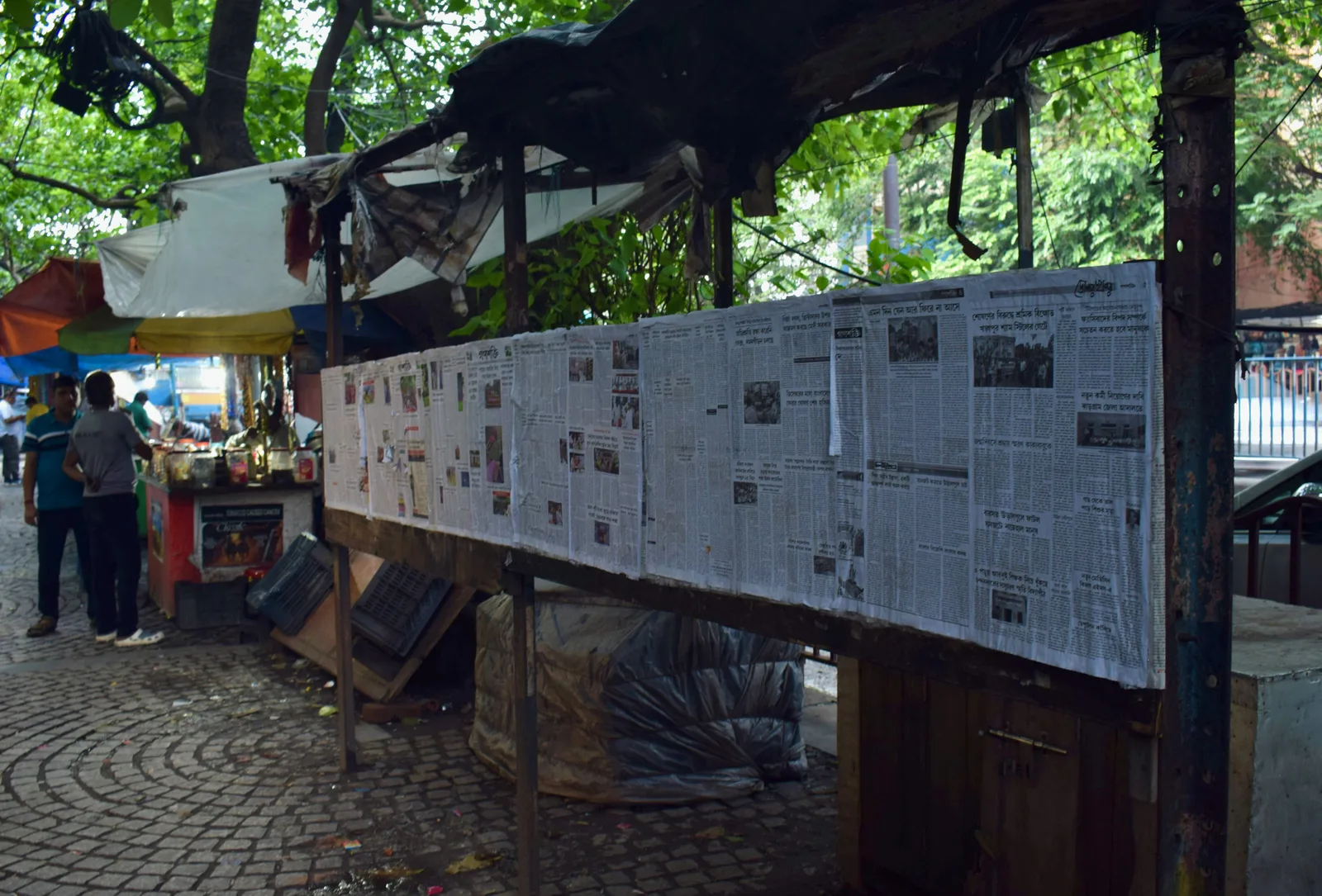 Bengali newspapers pinned up at a roadside stall