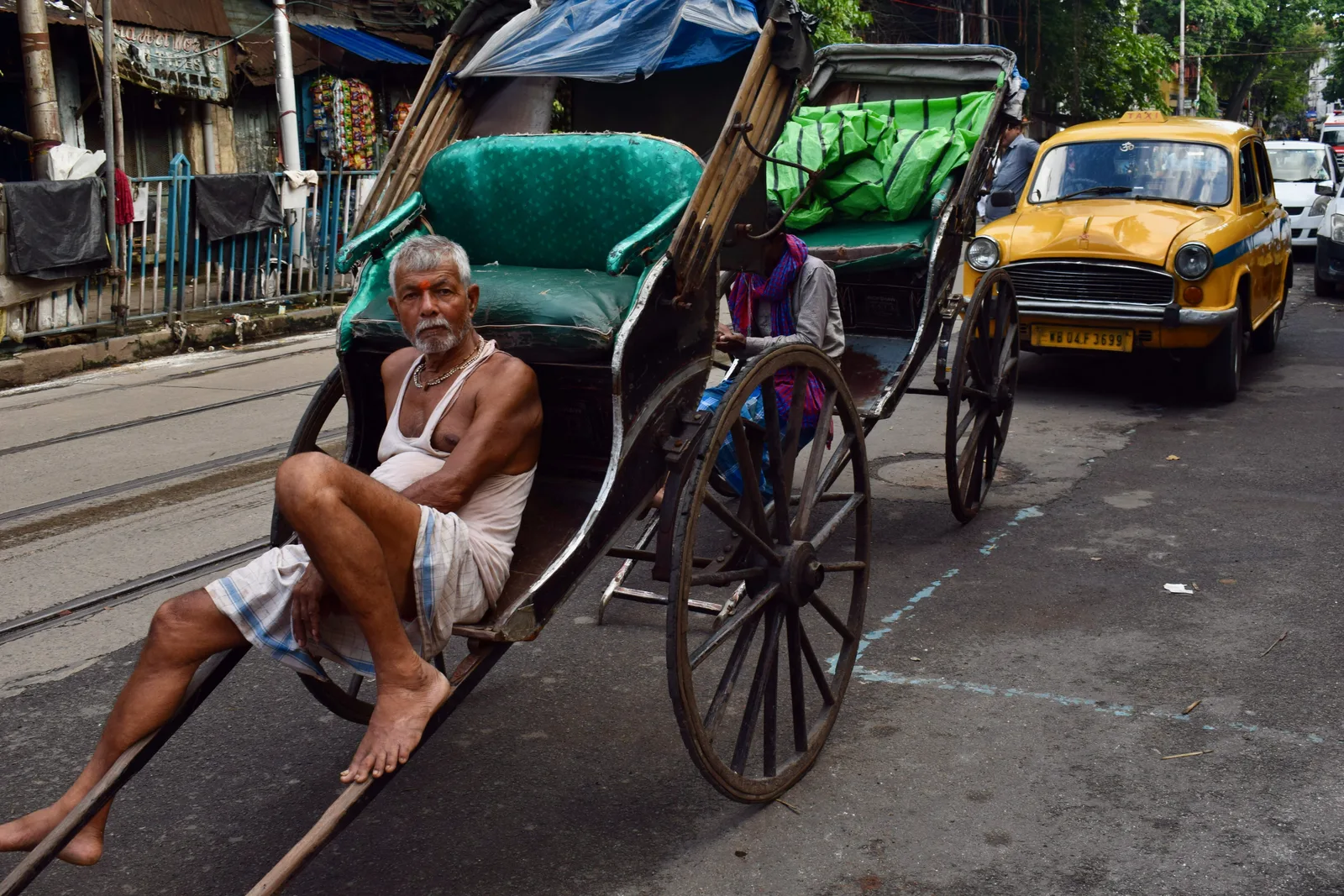 Rickshaw puller resting amid city traffic